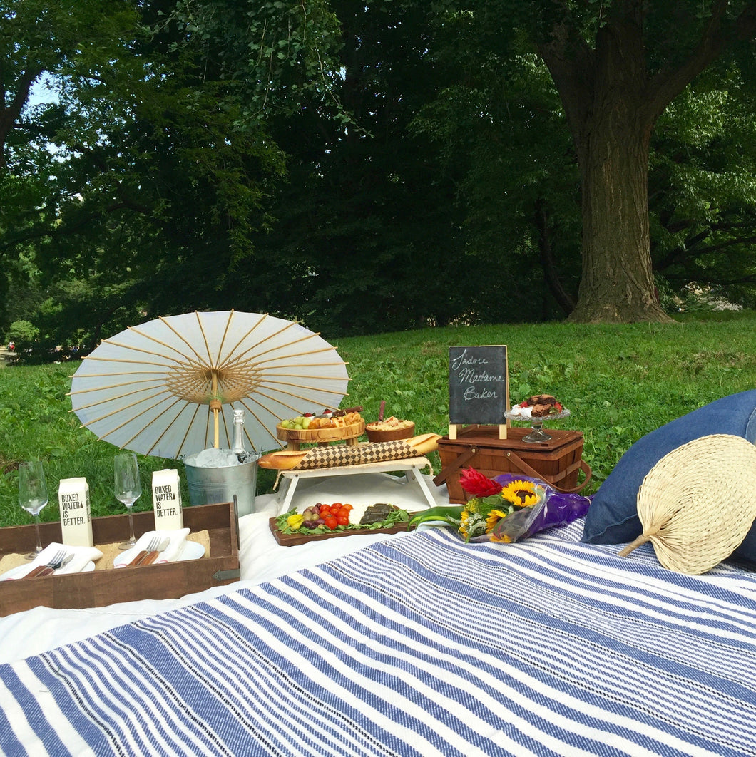 Picnic setup with blankets, pillows, and parasol.