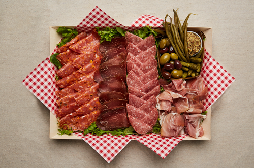 Plate of cured meats, cornichon, dilly beans, and olives